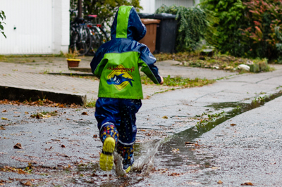Im Regen spielendes Kind